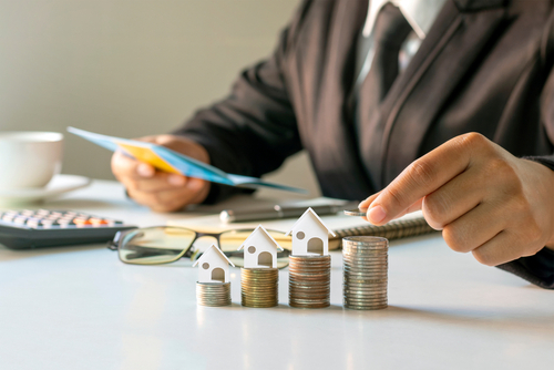 Businessman,Putting,Coins,On,A,Pile,Of,Coins,With,Financial